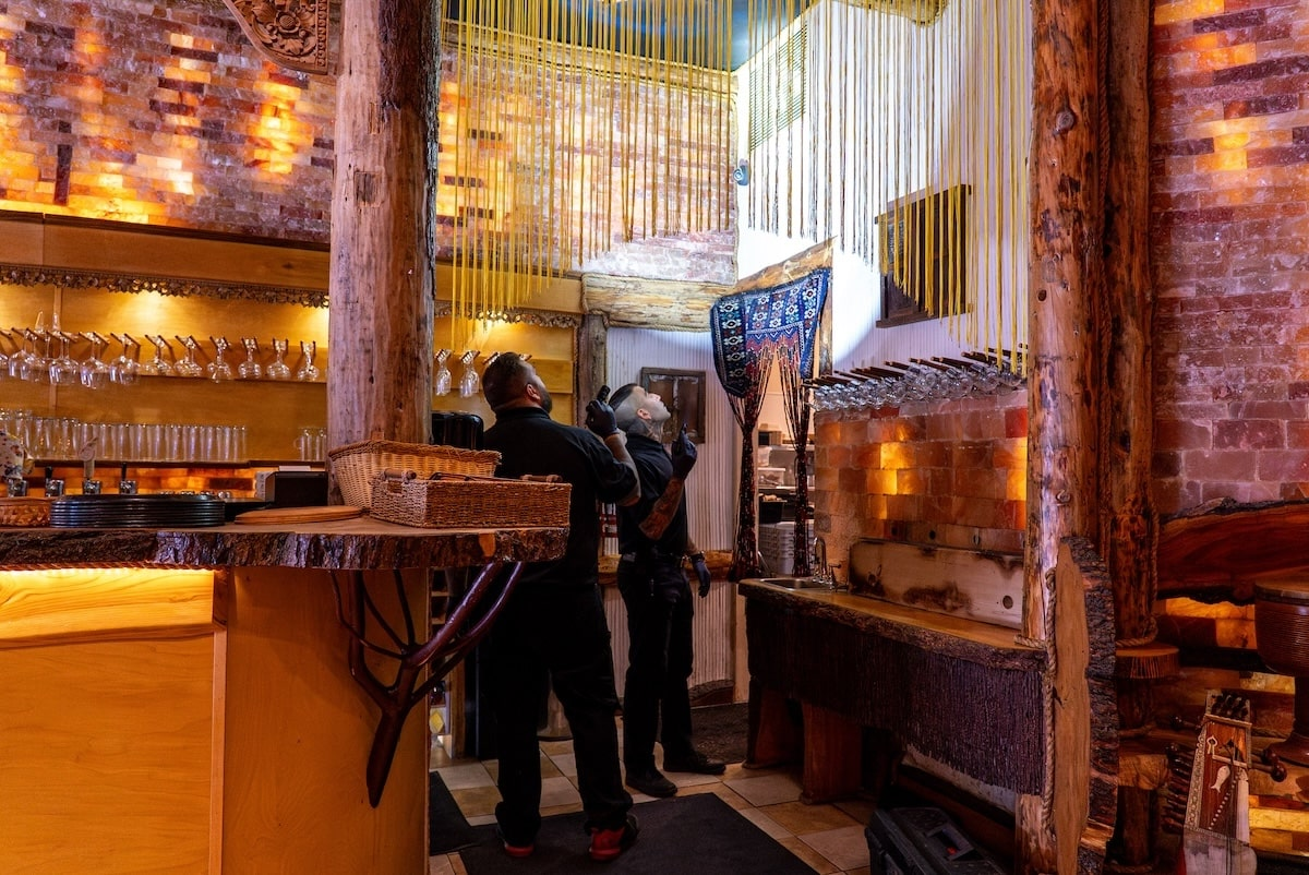 Two Phantom Pest Control technicians in gloves checking a restaurant ceiling with flashlights