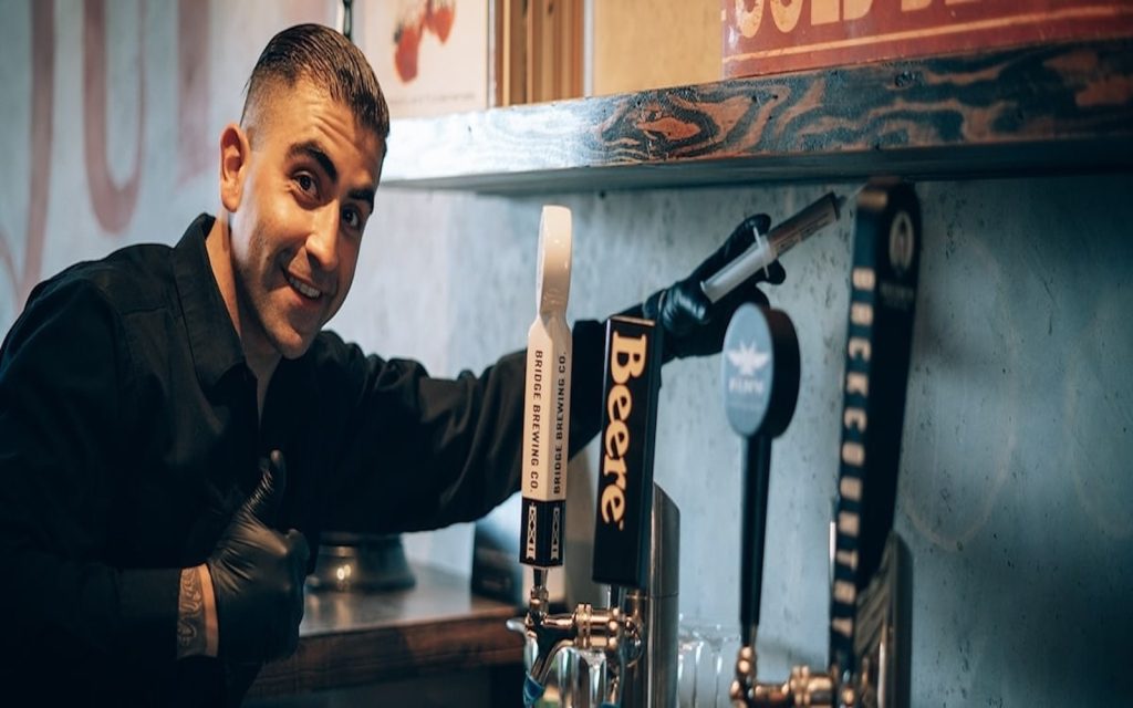 Phantom technician in black gloves beside the beer taps behind a bar counter