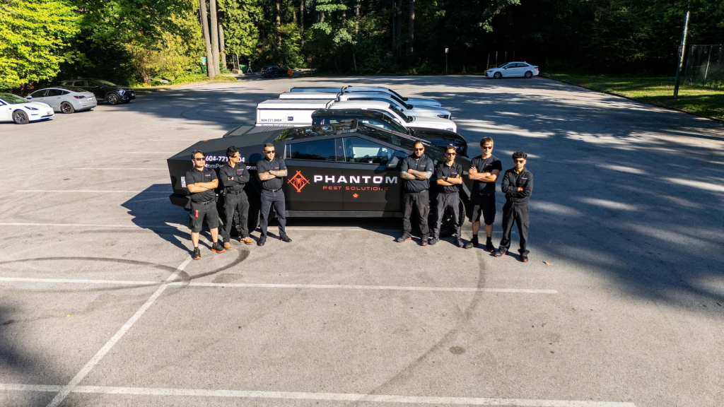 Seven Phantom technicians standing beside a branded service vehicle