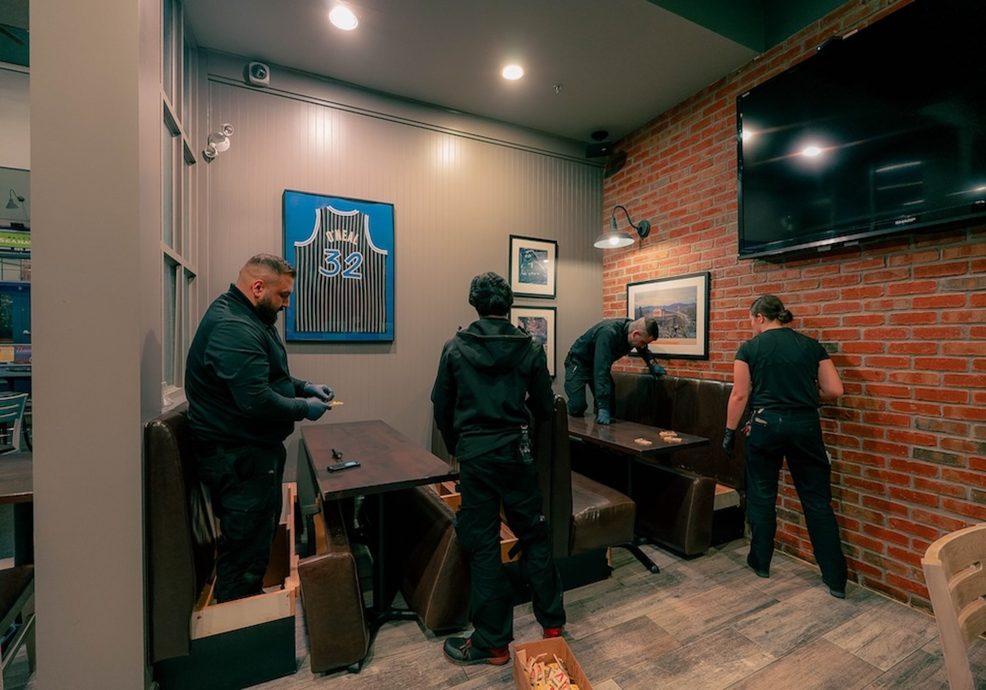 Four Phantom Pest Control technicians inspecting booth seating and walls in a commercial interior