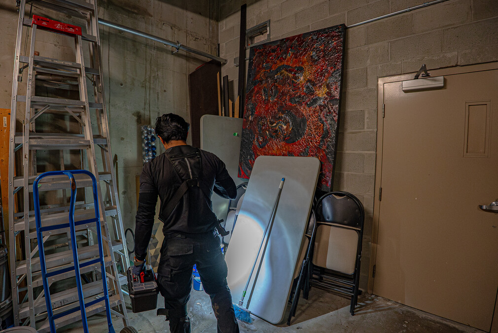 Phantom Pest Control technician with a flashlight and toolbox checking a storage room