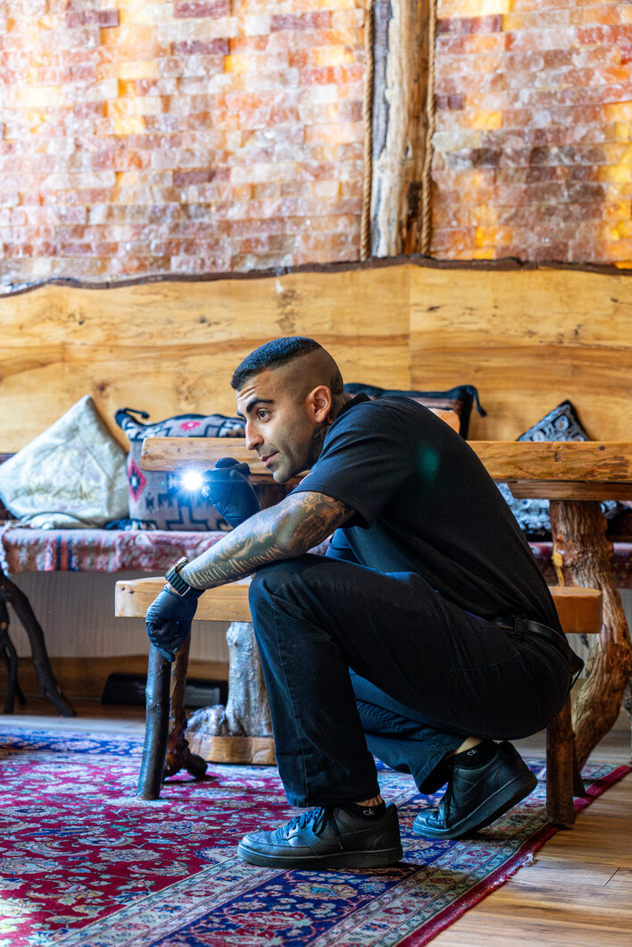 Phantom Pest Control technician shining a flashlight under a bench during an indoor inspection